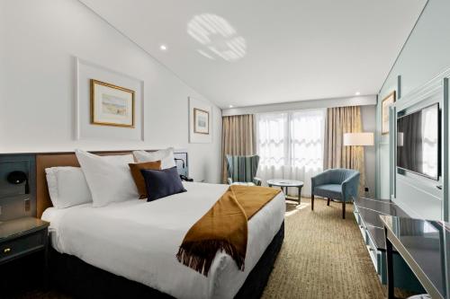 Cette chambre comprend un grand lit et un bureau. dans l'établissement Millennium Hotel Queenstown, à Queenstown