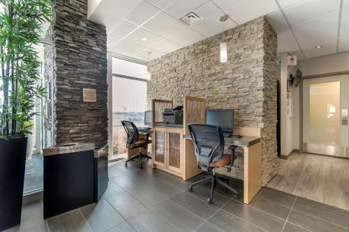 an office with a stone wall and desks and chairs at Best Western Plus Airport Inn & Suites in Saskatoon