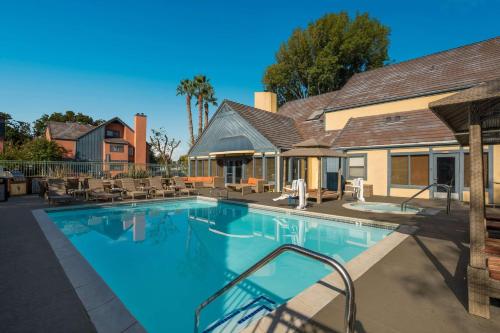a swimming pool with chairs and a house at SenS Suites Livermore; SureStay Collection by Best Western in Livermore