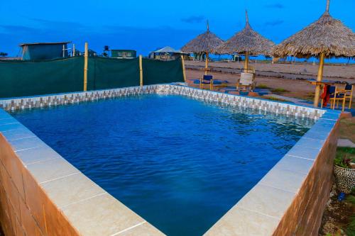 una piscina en la playa con sombrillas en Amanya 2-Bed Lioness Family Tent in Amboseli, en Amboseli