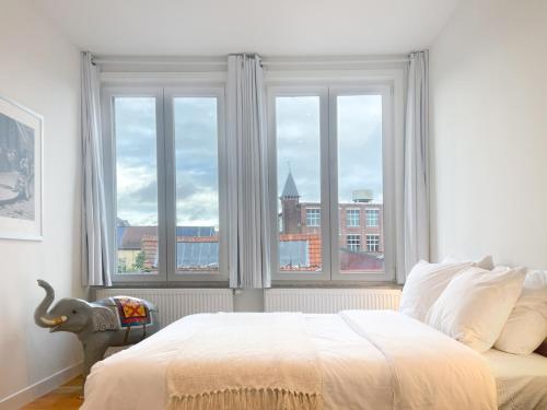 ein Schlafzimmer mit einem Bett und einem großen Fenster in der Unterkunft Appartement spacieux & calme avec vue sur l'Escaut in Tournai