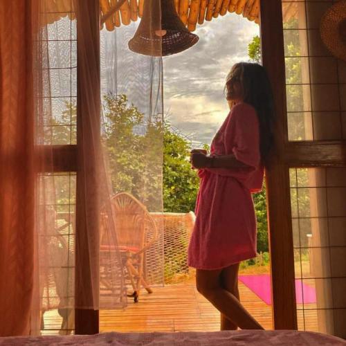 a girl in a red dress standing in front of a window at Laguna Rosa Glamping in Coveñas