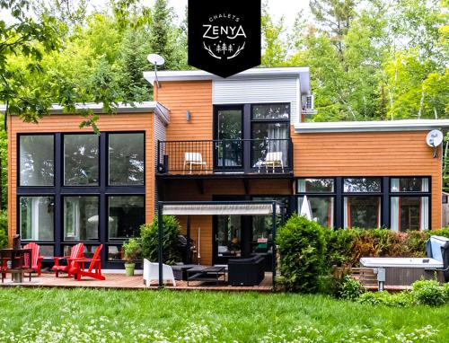 a house with black windows and red chairs in the yard at Chalet Villa Bianca Spa in Sainte Béatrix