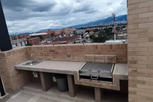 una cocina al aire libre con una parrilla en una pared de ladrillo en Aparta estudios central Con ascensor 503, en Bogotá