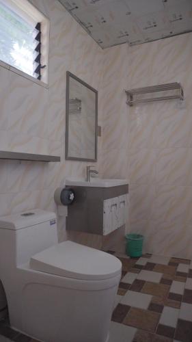 a bathroom with a white toilet and a sink at Speed 8 Inn Moalboal in Moalboal