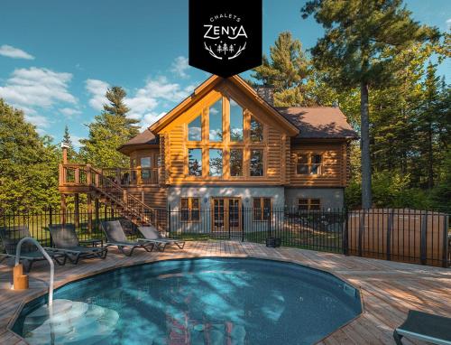 a log cabin with a swimming pool in front of a house at Chalet White Wolf SPA at Fiddler's Lake in Mille-Isles