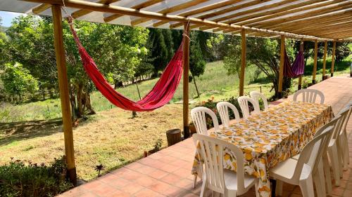 蒂瓦索薩的住宿－Corazón de la Montaña，一张桌子、白色的椅子和红色的吊床