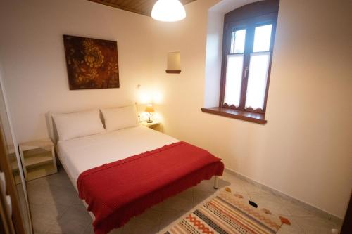 een slaapkamer met een bed met een rode deken en een raam bij Casa de la Vita in Katochorion