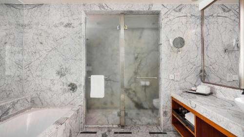 a bathroom with a shower and a tub and a sink at InterContinental Marine Drive Mumbai by IHG in Mumbai