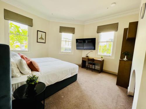 a bedroom with a bed and a desk with a television at Clarendon Hotel in Melbourne