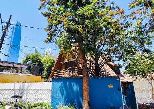 un árbol frente a una casa con una pared azul en Maktub Costanera - Hostal Boutique, en Santiago
