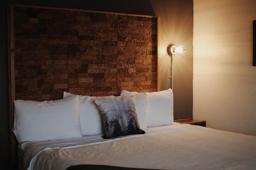 a bed with white pillows and a brick wall at Adrift Hotel in Long Beach