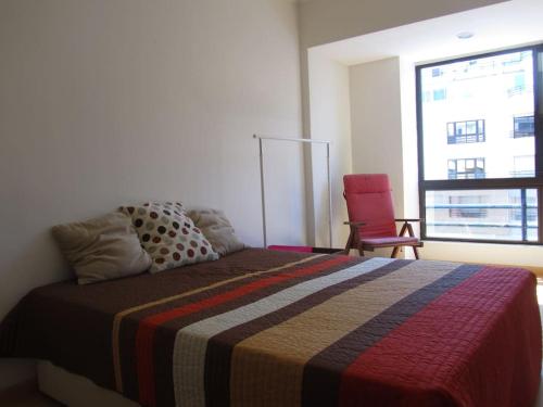 - une chambre avec un grand lit et une chaise rouge dans l'établissement ENJOY OCEAN BEACH LIFE at COSTA DA CAPARICA!, à Costa da Caparica