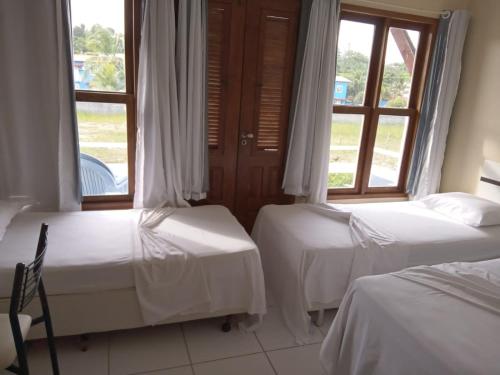 two beds in a room with two windows at APARTAMENTO 3 quartos no Taperapuan Duplex 450 mt da praia in Porto Seguro