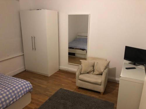 a room with a chair and a mirror and a bed at Common 2 in London