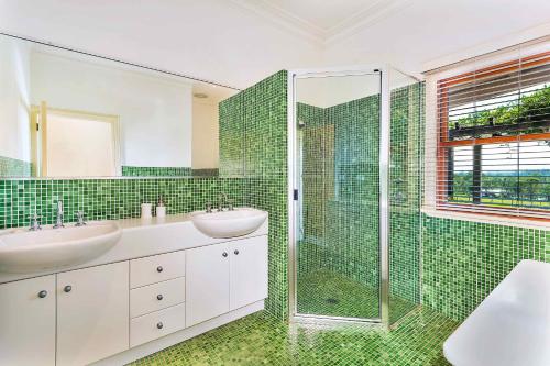 La salle de bains carrelée de couleur verte est pourvue de deux lavabos et d'une douche. dans l'établissement The Ballabourneen House, à Lovedale