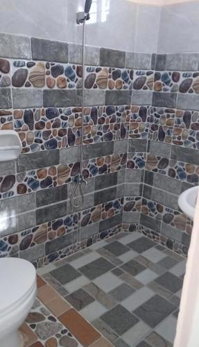 a bathroom with a shower with a toilet and a tiled floor at D&D Travellers INN in Puerto Princesa City
