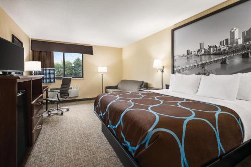 a hotel room with a bed and a desk at Super 8 by Wyndham Grove City in Grove City