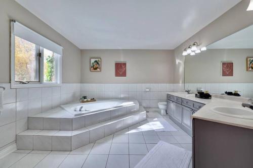 uma ampla casa de banho branca com uma banheira e um lavatório. em Cheerful 7 bedrooms Villa with Hot tub & Pool. em Mississauga