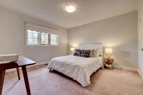 ein Schlafzimmer mit einem weißen Bett und einem Fenster in der Unterkunft Cheerful 7 bedrooms Villa with Hot tub & Pool. in Mississauga