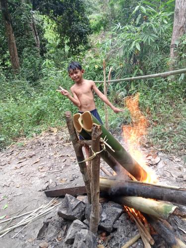 a young boy standing next to a fire at Bee Bee's Chalets home stay and trekking in Banlung