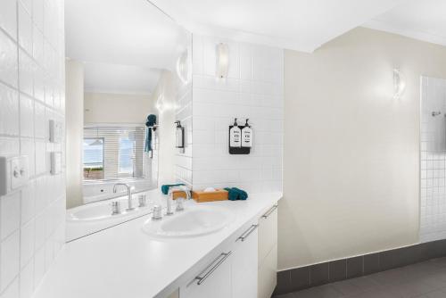 a white bathroom with a sink and a mirror at Lorne beach views at the cumberland in Lorne