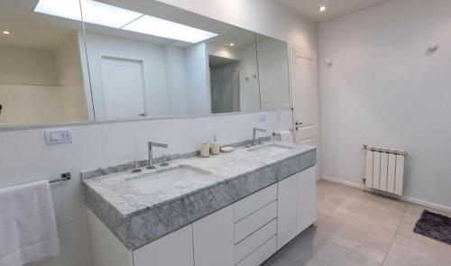 baño con 2 lavabos y espejo grande en Fliphaus Salvador 5500 - 3 Bd Pool & Bbq en Buenos Aires