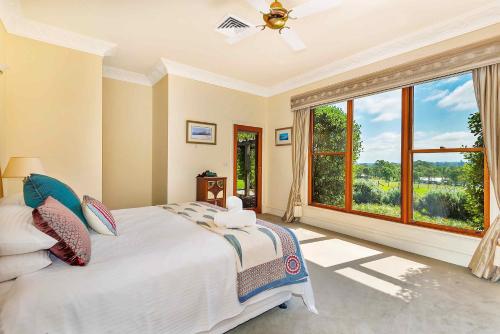 a bedroom with a large bed and a large window at The Ballabourneen Estate in Lovedale
