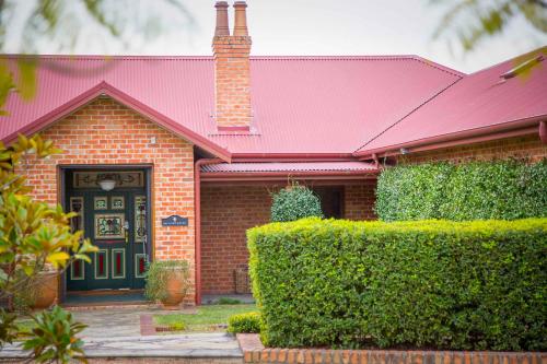 a brick house with a red roof and a green door at The Ballabourneen Estate in Lovedale