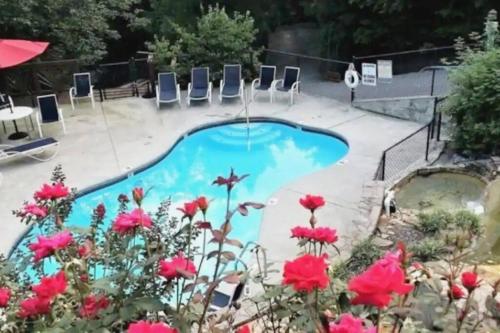 a pool with chairs and flowers in a yard at Cozy Studio Cabin, w/ Hot Tub! in Gatlinburg