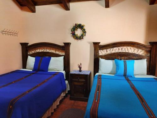 a bedroom with two beds with blue sheets and a table at Hotel Casa Sofia in Antigua Guatemala