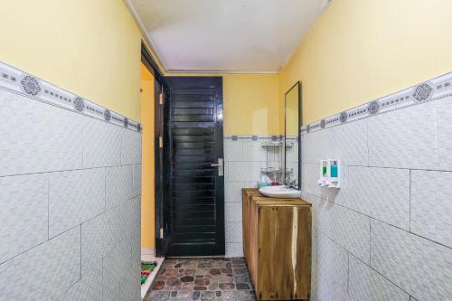 ein Bad mit einem Waschbecken und einer schwarzen Tür in der Unterkunft The Salang Guest House in Nusa Penida