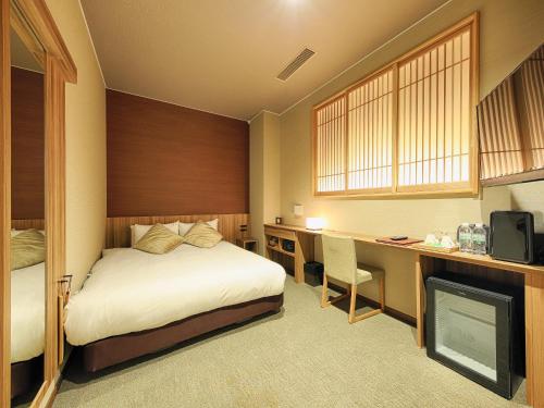 Habitación de hotel con cama, escritorio y TV. en HOTEL CUORE Kyoto Shijo Omiya en Kioto