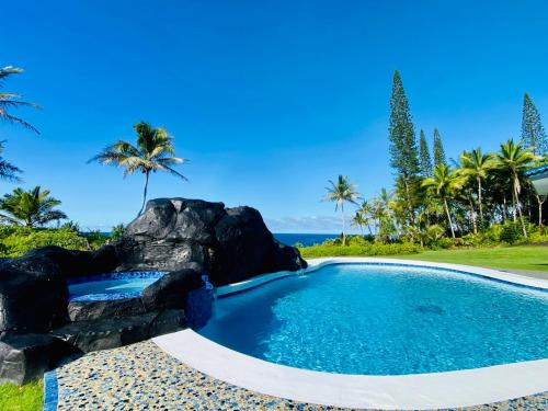 a swimming pool with a rock and the ocean at Wild Blue Water in Pahoa