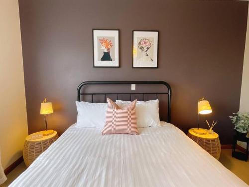 Stunning Hobart 3-bed home- close to shopping centers في Glenorchy: غرفة نوم بسرير ابيض كبير ومصباحين