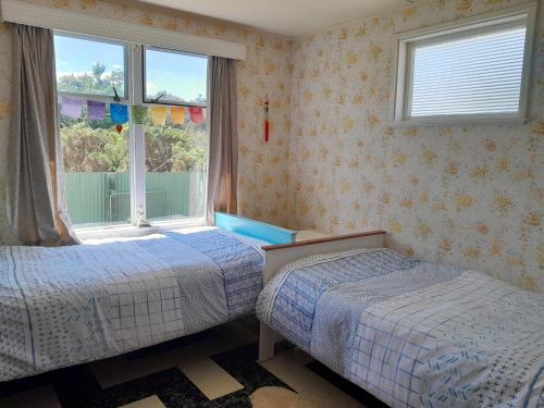 sypialnia z 2 łóżkami i oknem w obiekcie Ironsands Cottage w mieście Patea