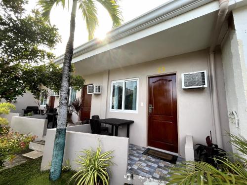 a house with a brown door and a palm tree at Ocean Bay Beach Resort in Dalaguete