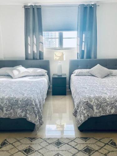 a bedroom with two beds and a window with blue curtains at Ocean Reserve Piso 9 - STR 2412 in Miami Beach