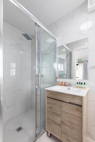 Un baño blanco con ducha y lavabo. en Solsen Flexi-Stay, en Auckland