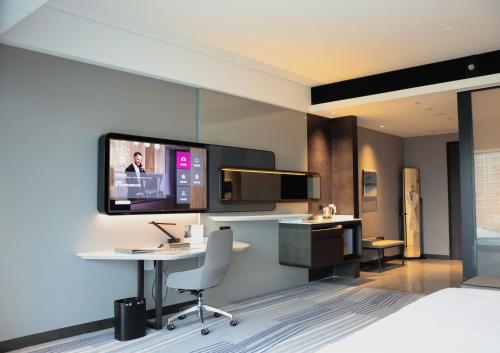 a hotel room with a desk and a tv on the wall at Crowne Plaza Xiamen Jimei Seaview by IHG-Free Mini Bar in Xiamen