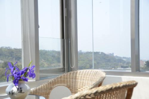 a table with two chairs and a vase with purple flowers at Rainbow Bridge B&B in Sanzhi