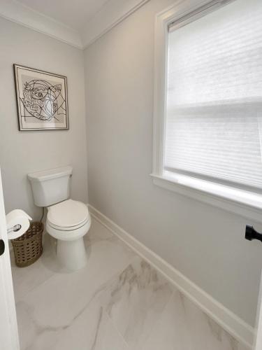 a white bathroom with a toilet and a window at New Construction Modern Luxury Retreat w 6 Beds in Southampton