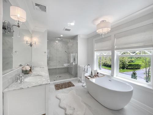 La salle de bains blanche est pourvue d'une baignoire et d'une douche. dans l'établissement Hampton Luxury Estate - New Construction Luxury Retreat in Southamptons, à Southampton