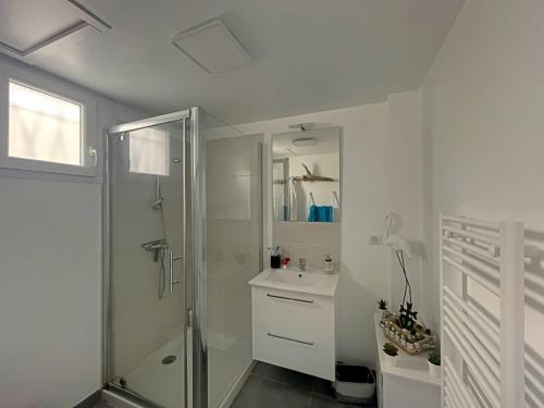 een witte badkamer met een douche en een wastafel bij Studio Saintes-Maries-de-la-Mer, 1 pièce, 3 personnes - FR-1-475-99 in Saintes-Maries-de-la-Mer