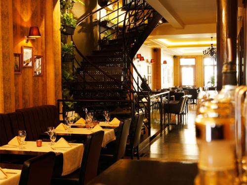 a restaurant with tables and chairs and a spiral staircase at Apartamenty Złota Nić in Opole