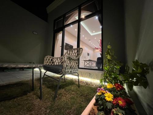 a chair in a room with a window and flowers at الأجنحة الرخامية فندقية in Buraydah
