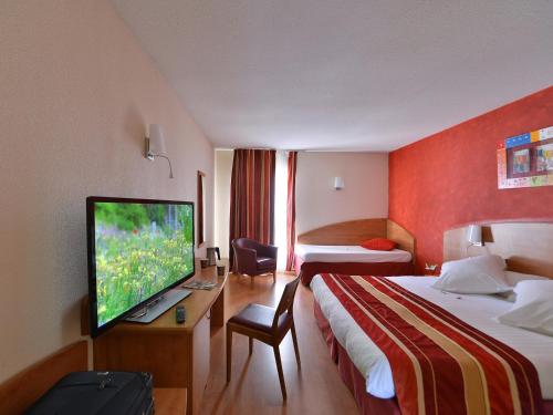 a hotel room with two beds and a flat screen tv at Kyriad N&icirc;mes Ouest A9 in N&icirc;mes