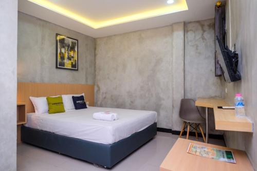 a bedroom with a bed and a desk and a table at Urbanview Hotel Syariah Artamara Tegal by RedDoorz in Tegal
