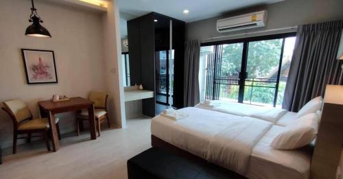 a bedroom with a bed and a table and a window at Premier Luxe Hotel โรงแรมพรีเมียร์ลักซ์ in Ban Nong Chaeng