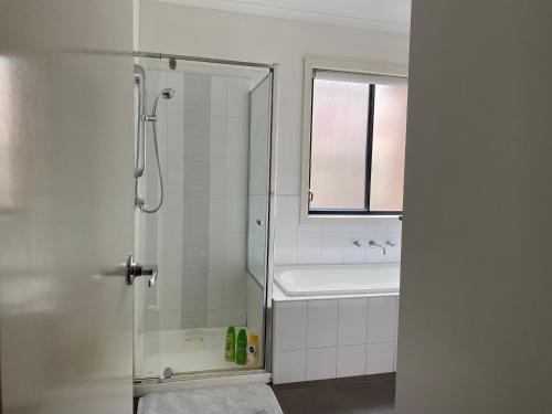 uma casa de banho branca com um chuveiro e um lavatório. em 4 Beds-Whole House-Black Knight Way-Kuranjang-Less than 30 minutes From Melbourne international airport em Melton